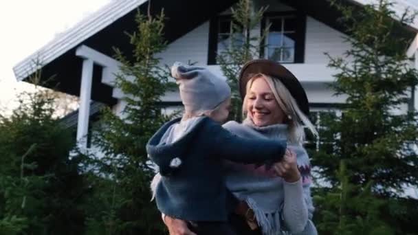 A young mother who holds a little boy in her arms and dances with him near the house at sunset — Stock Footage A young mother who holds a little boy in her arms and dances with him near the house at sunset Royalty Free Stock Video