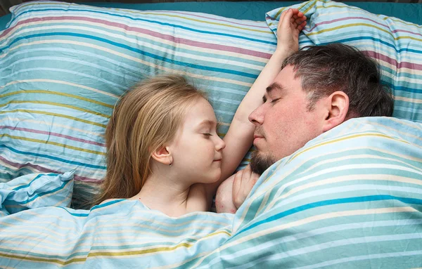 Niña 5 años durmiendo acurrucada con papá en la cama — Foto de Stock