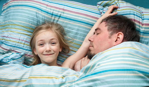 Niña 5 años durmiendo acurrucada con papá en la cama — Foto de Stock