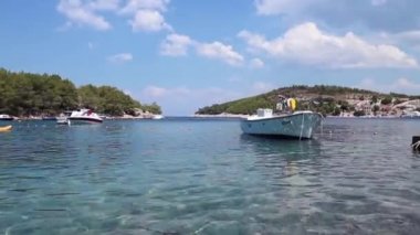 Adriyatik Denizi 'ndeki Hvar adasındaki körfezde demirli küçük, beyaz bir tekne yüzeyde yavaşça sallanıyor.