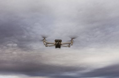 Beyaz Fimi hava aracı, gün batımında bulutlu gökyüzüne doğru uçuyor.