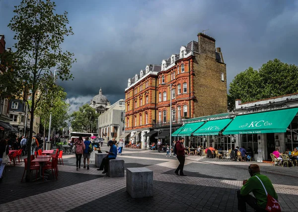 Londra, İngiltere - 10 Ağustos 2018: Londra sokaklarında yaz yağmurundan önce, harika, eski tuğlalı evler ve sokak kafeleri insanlarla dolu