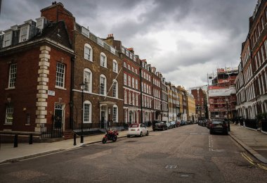 Londra, İngiltere - 12 Ağustos 2018: Yağmurlu gökyüzünün altında kırmızı tuğlalı evler dizili harika Londra sokakları