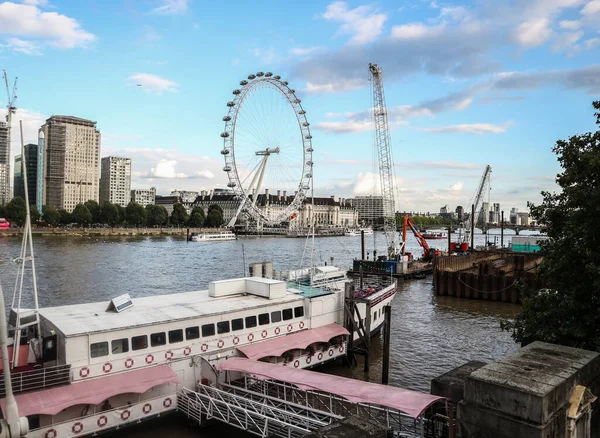 Londra, İngiltere - 13 Ağustos 2018: Londra Gözü, popüler dönme dolap Thames nehri ve limanında güneş batarken demirlemiş gemilerle birlikte