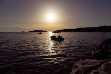 Rogoznica sahilinde harika bir yaz günbatımı, körfeze demir atmış teknelerin siluetlerini oluşturuyor.