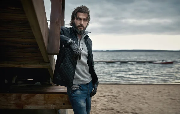 Portret van een volwassen knappe jongen die rusten op de herfst strand — Stockfoto