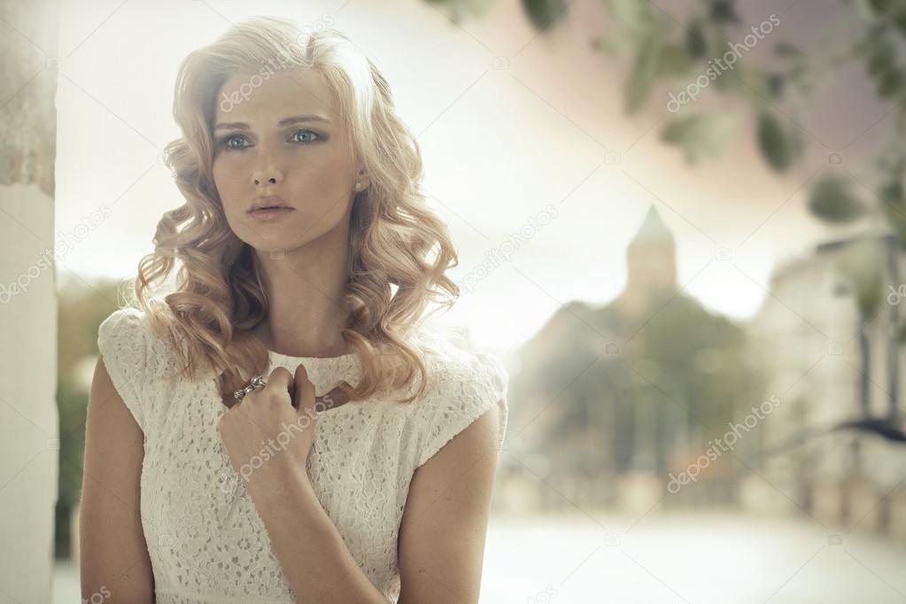 Blond lady with curly hairstyle posing outdoor