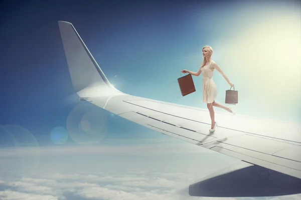 Привлекательная блондинка с пакетами на крыле самолета — стоковое фото