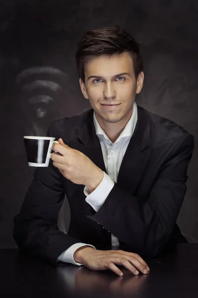Smart young businessman holding the cup of vaporous coffee — Stock Photo, Image