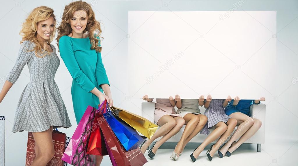 Group of cheerful girlfriends advertising shopping sales