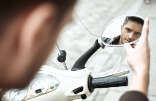 Handsomke man looking at himself in bike's mirror — Stock Photo, Image
