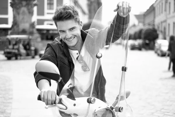 Portrait of happy young man riding a scooter — Stock Photo, Image