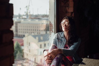 Güzel, orta yaşlı bir kadın pencerede oturuyor.