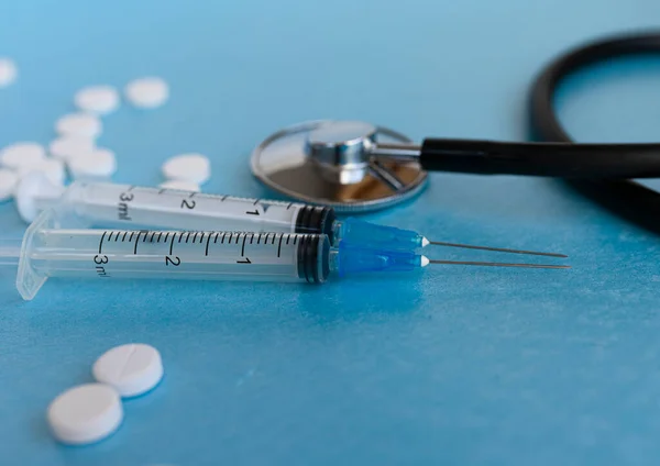 Coronavirus prevention and treatment healthcare concept - syringe, pills, stethoscope on a blue background. selective focus