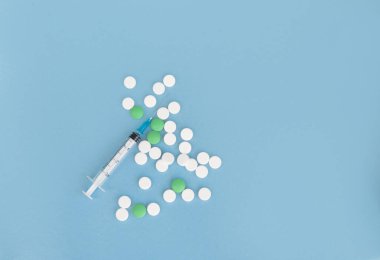 Şırınga ve mavi arka planda bir sürü hap. Uzayı kopyala Düz yatıyordu. Coronavirus ve mevsimsel hastalık tedavi konsepti