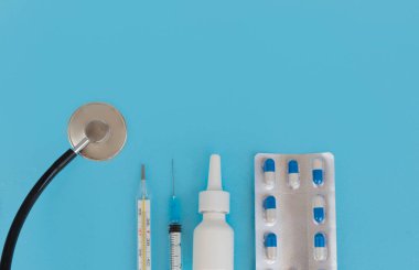 Haplar, termometre, şırınga, steteskop parçası, mavi arka planda burun spreyleri, üst manzara, kopyalama alanı. Tıp ve mevsimsel hastalık konsepti fotoğrafı. Coronovirus. Geniş görüş açısı, düz yatış
