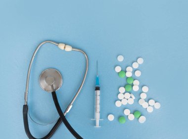 Stetoskop, şırınga, mavi arka planda bir sürü hap. Uzayı kopyala Düz yatıyordu. Coronovirüs tedavisi kavramı