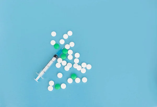 Şırınga ve mavi arka planda bir sürü hap. Uzayı kopyala Düz yatıyordu. Coronavirus ve mevsimsel hastalık tedavi konsepti
