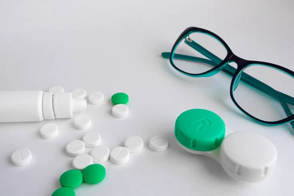 On a white background are items for improving vision, glasses, eye drops, pills and vitamins, contact lenses for improving vision. The concept of vision improvement