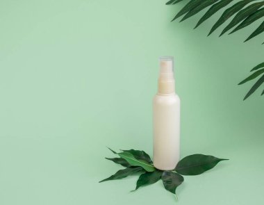 Beyaz kozmetik şişesi, tropikal yapraklı yeşil bir arka planda cilt bakımı için spey şeklinde. Biyokozmetik ürünler için ambalaj tasarımı. Promosyon kozmetik ürünü. Boşluğu kopyala.