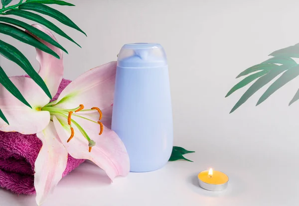 Beyaz mermer arka planda mavi duş jeli, spa salonu konsepti, zambak çiçeği, havlu, mum, tropikal yapraklar. Boşluğu kopyala