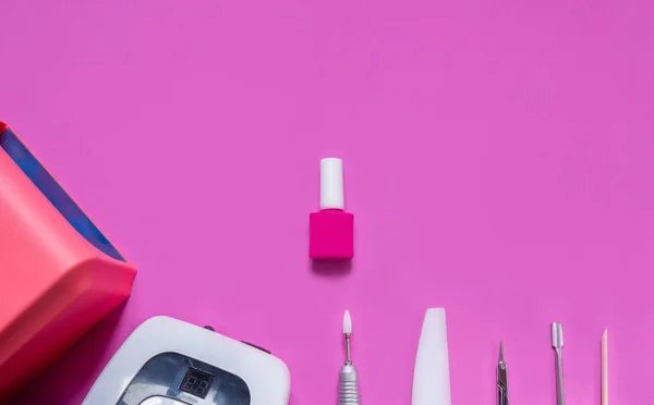 Pembe arka planda manikür ve güzellik aksesuarları. Ana planda çivi cilası, tırnak törpüsü, lamba, makas ve ev ve kuaför işlemleri için diğer malzemeler. Yukarıdan manzara. Kopyalamak için alan. Düz yatıyordu