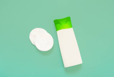 Yüz temizleyici ve yüz kremi ve mavi arka planda pamuk pedleri olan bir şişe. Çevre dostu kozmetik konsepti. Düz konum, üst görünüm, kopyalama alanı