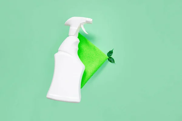 Püskürtme şişesi beyaz temizleyici ve yeşil temizlik bezi, yeşil arka planda yeşil yapraklar. Düz yerde, üst tarafta. Çevre dostu temizlik ve temizlik konsepti. Boşluğu kopyala