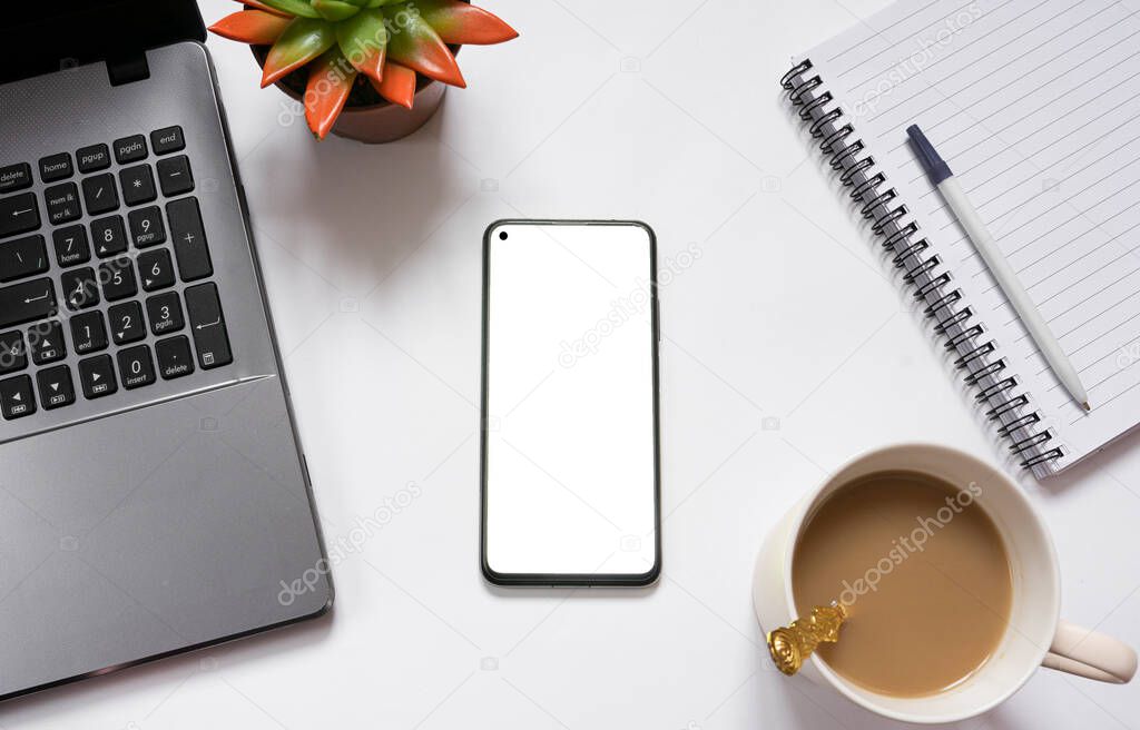 White office desk with laptop, coffee, notepad, houseplant, smartphone with white screen. Office workplace concept. view from above. copy space. Flat lay