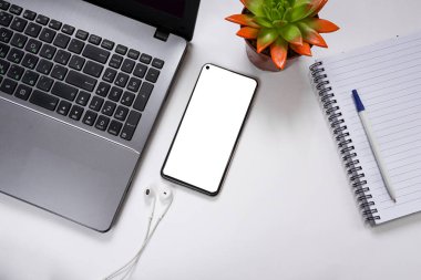 Beyaz ekranlı akıllı telefon, defter, defter, not defteri, kalem, kulaklık beyaz arka planda. Öğrenci masaüstü konsepti. kopyalama alanı. Düz yatıyordu. en üstteki görünüm
