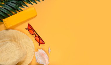 Seyahat aksesuarları, gözlükler, güneş kremi, şapka, parlak sarı bir arka planda deniz kabuğu ve mesaj için boş bir alan. Seyahat ya da tatil konsepti. Yaz dönemi. Düz yatıyordu. Pankart