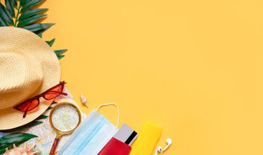 Yaz dönemi. Şapka, kırmızı gözlük, tıbbi maske, güneş kremi, sarı arka planda cüzdan. Nezle salgını ve mesaj için yeri olan virüsler sırasında deniz kenarında tatil için bir setin maketi. 