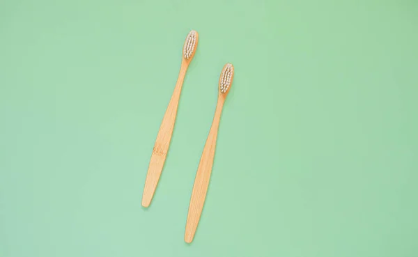 Natural bamboo toothbrushes with white bristles on a mint green background. The concept of an environmentally friendly toothbrush without harm to nature. Flat lay.view from above. copy space for text