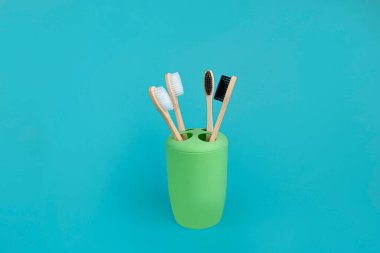 Dört bambu diş fırçasından oluşan yeşil diş fırçası seti. Mavi bir arka plan. Doğal organik oral bakım ürünü kavramı. Atık yok, doğaya zarar yok. Boşluğu kopyala.