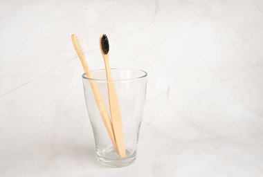 Banyodaki mermer arka planda şeffaf camlarda bambu diş fırçaları. Oral bakım konsepti. Doğal organik banyo kozmetik ürün konsepti. Plastik atık yok. metin için boşluk kopyala