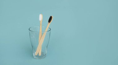 Mavi arka planda şeffaf camlarda bambu diş fırçaları. Oral bakım konsepti. Doğal organik banyo kozmetik ürün konsepti. Plastik atık yok. metin için boşluk kopyala. Pankart