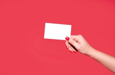 Güzel manikürlü bir kadın elinin altında indirim kartı, kartvizit ve kırmızı arka planda beyaz bir kağıdın kopyası var. Tasarım şablonu. Yerleşim planı. metin için boşluk kopyala