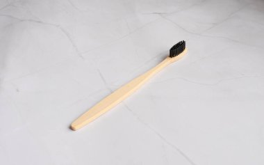 Beyaz mermer arka planda doğal ahşap bambu diş fırçası. Ağız ve sakız bakımı konsepti. Geri dönüştürülebilir doğal organik diş fırçası. Düz konum, üst görünüm, metin için boşluk kopyala