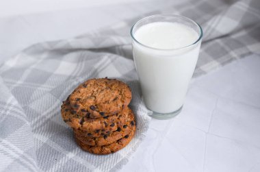 Bir bardak süt ve açık beyaz arka planda ev yapımı yulaflı kurabiyeler. Düzgün beslenme kavramı. Köyde kahvaltı var. metin için boşluk kopyala. en üstteki görünüm