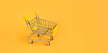 Parlak sarı arka planda boş bir alışveriş arabası. Alışveriş, online alışveriş konsepti, Kara Cuma, indirim, hızlı dağıtım, online alışveriş. Metin ve afiş için boşluk kopyala. maketleme