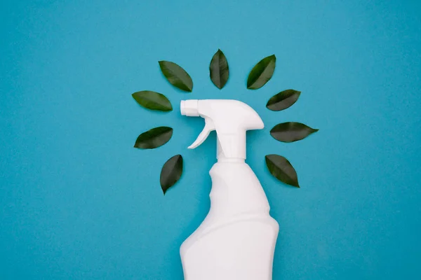 Plastic spray bottle for safe cleaning and green leaves on a blue background. Natural organic cleaning agent.Bio organic. Eco Cleaning spray. Eco concept of house cleaning. copy space. top view