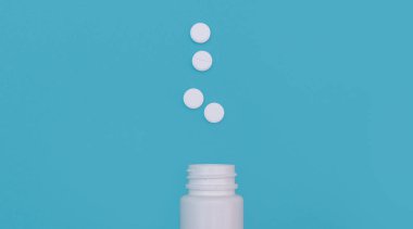 Mavi arka planda bir şişe ve birkaç hap. İlaç ve tedavi konsepti. Sunumlar, dersler, tasarım üst görünümü için beyaz tabletler. Düz yatıyordu. kopyalama alanı. maketleme