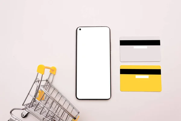 白い画面 ショッピングバスケット 白い背景に2枚のクレジットカードでスマートフォン オンラインショッピング ショッピング ブラックフライデー 割引の概念 フラットレイアウト トップビュー モックアップ — ストック写真