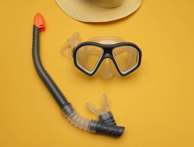 Sarı arka planda şnorkel ve şapka parçalı dalış maskesi. Havuzda ya da denizde yüzmek için bir maskenin minimalist fotoğrafı. Merkezi kompozisyon. Denizde tropikal yaz tatili kavramı.