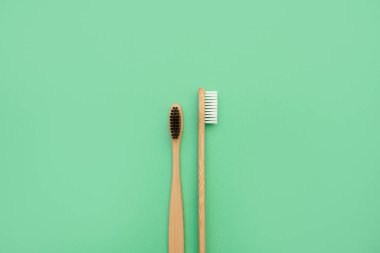 Nane yeşili arka planda doğal bambu diş fırçasının ön ve yan görüntüsü. İsraf yok, naylon yok. Diş fırçalarının organik işlemleri. Diş eti ve diş eti bakımı için konsept. Boşluğu kopyala, üst görünüm.
