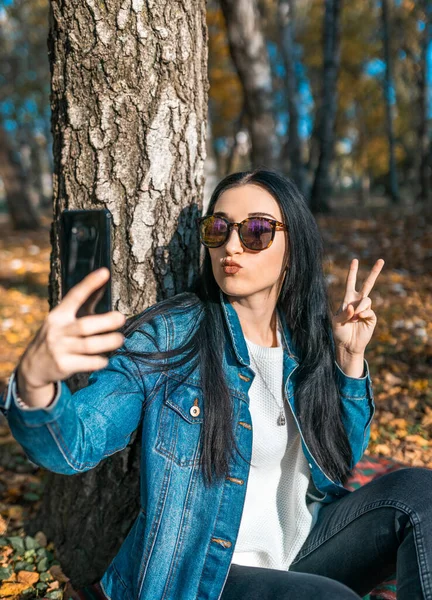 Young Beautiful Woman Sunglasses Looks Phone Takes Selfie Autumn Park — Stock Photo, Image