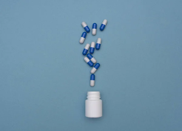 许多蓝色药丸在蓝色背景下从罐子里倒出来 医学和健康概念 维生素 抗生素 从上面看 平躺在床上 — 图库照片