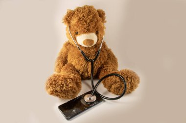 Steteskoplu ve bozuk telefonlu oyuncak ayı.
