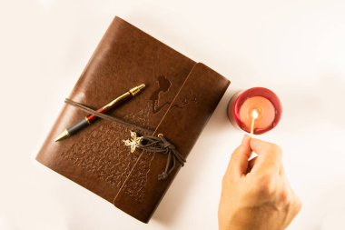 Yanında kalem ve mum olan kişisel defter.