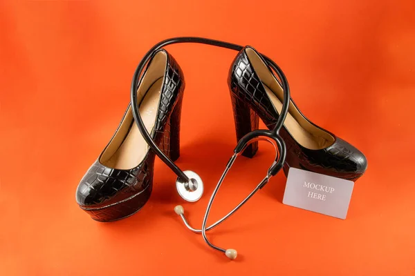 Heeled shoes with stethoscope and business card on a red background